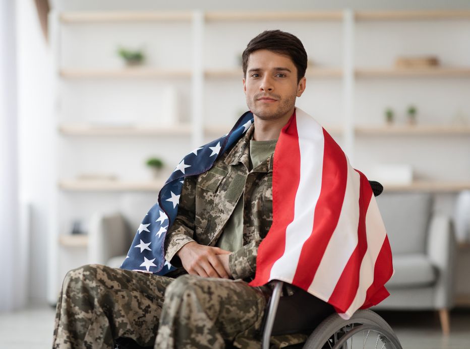 disabled veteran in wheelchair with US flag draped on him